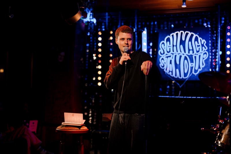 Comedian mit Mikrofon vor dem blauen SCHNACK Neonschild