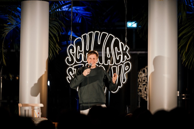 Comedian auf der Bühne vor dem SCHNACK Neonschild